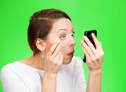 exhausted woman looking in a mirror isolated on green background